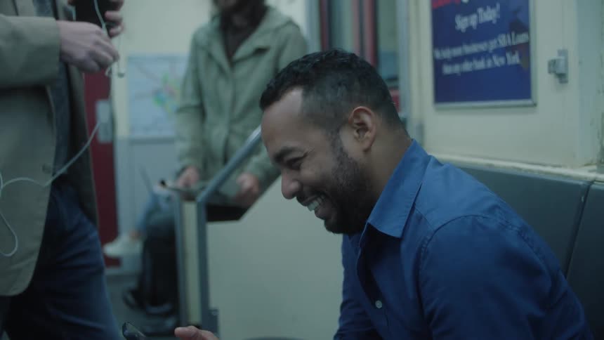 Men laugh together while riding a subway