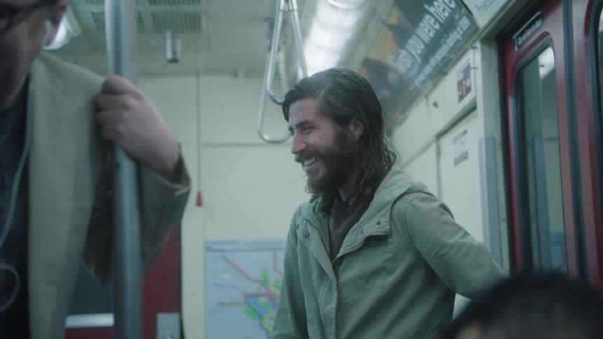 Men sitting and standing in a train cabin laughing
