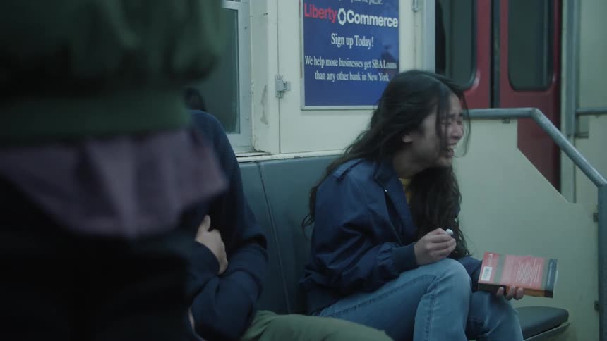 Two young people sitting inside the train laughing