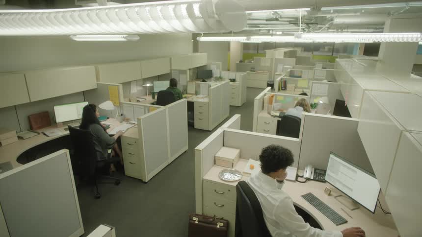 A large office with white furniture and several people sitting working