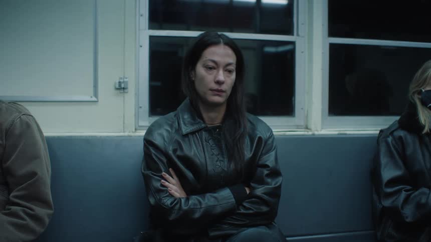 Woman sitting on the bench of a moving train with a sad facial expression
