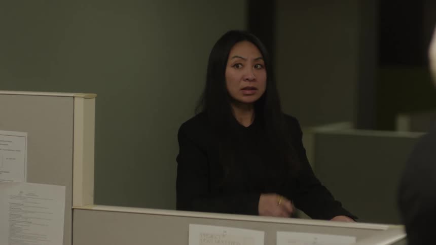 A businesswoman wearing a blazer jacket is talking to someone in the office when suddenly she realizes something