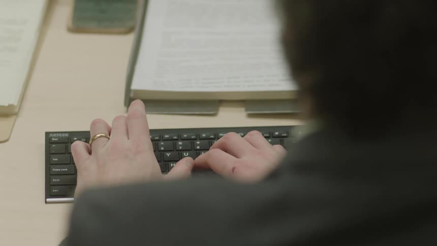 Male office worker sits and uses a computer keyboard