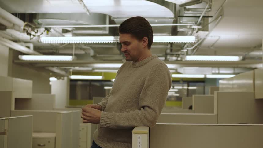 Worker leans against a low cubicle wall while talking
