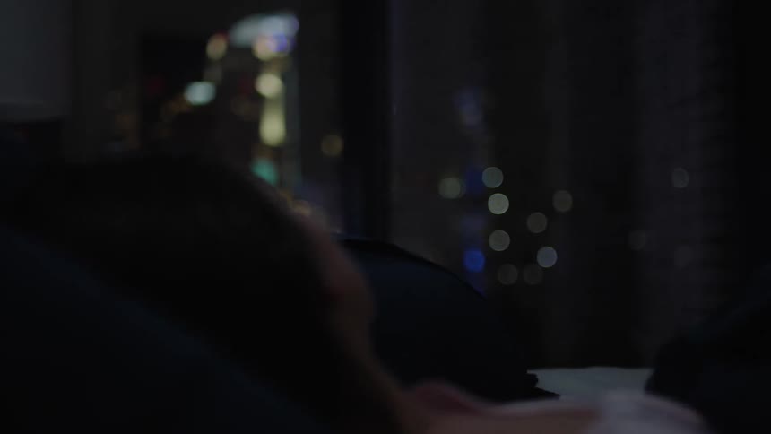A woman is resting in bed looking out the window