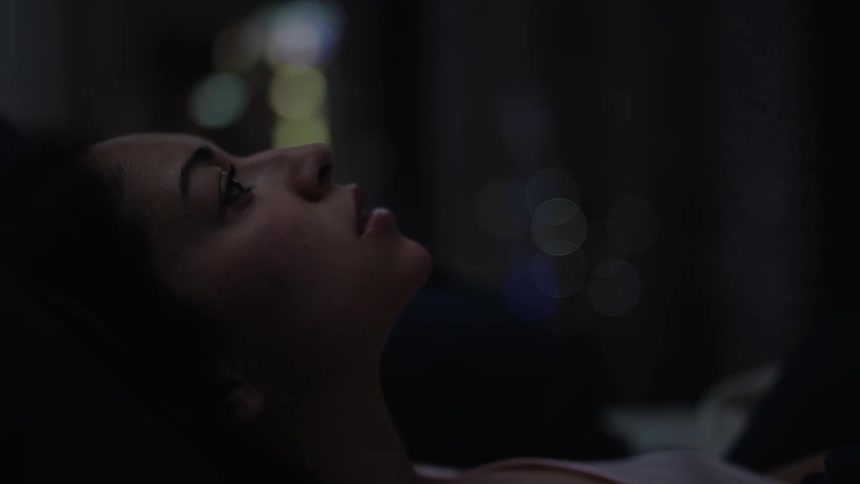 A young woman shuffles around in bed