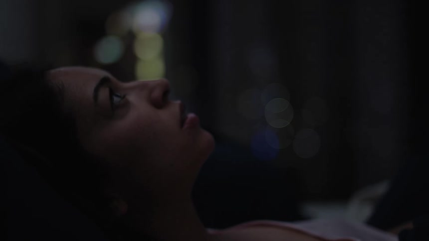 Close up of the face of a woman yawning in bed at night