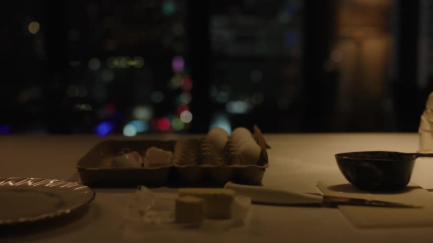 Table with utensils and a persons hands preparing an omelet
