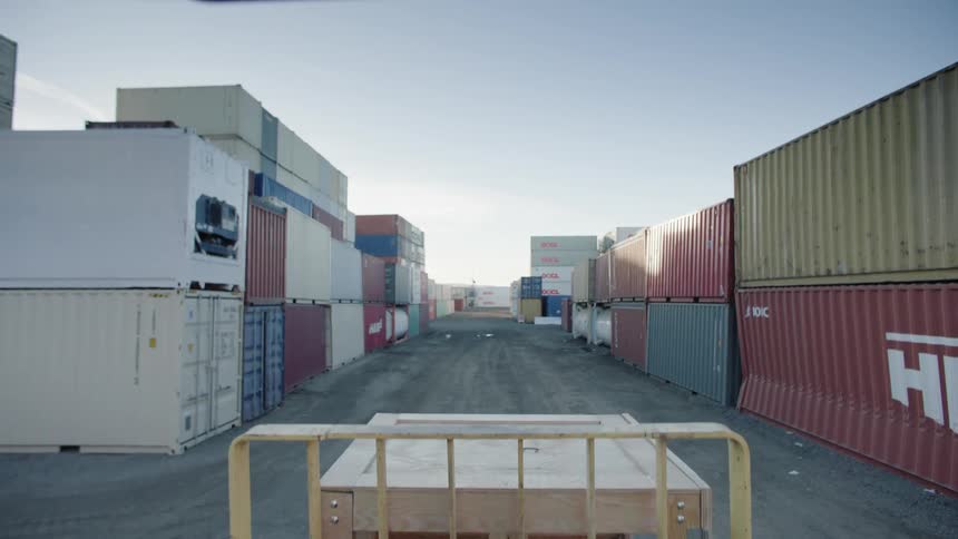 A forklift lifts a crate into view at a shipping yard