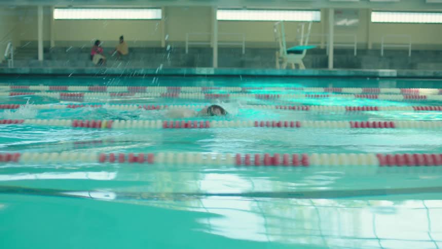 A man dives into a pool and swims
