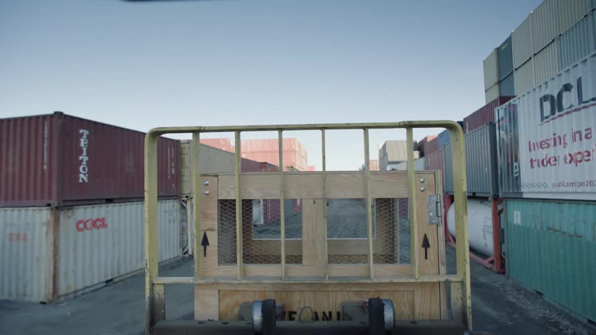 Mobile wooden box car outdoors with containers around a distribution center