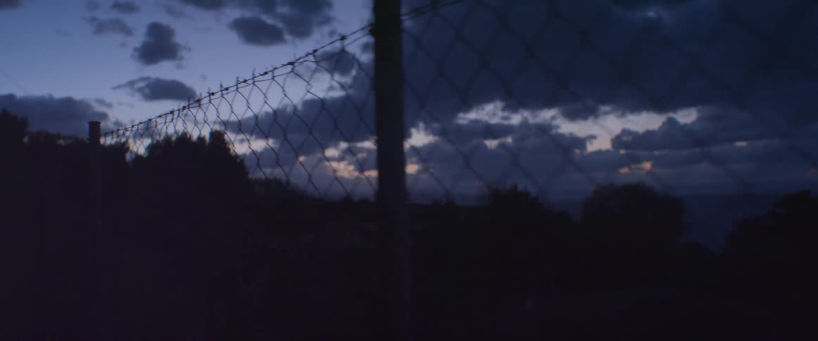 A barbed wire fence on a dark, cloudy night