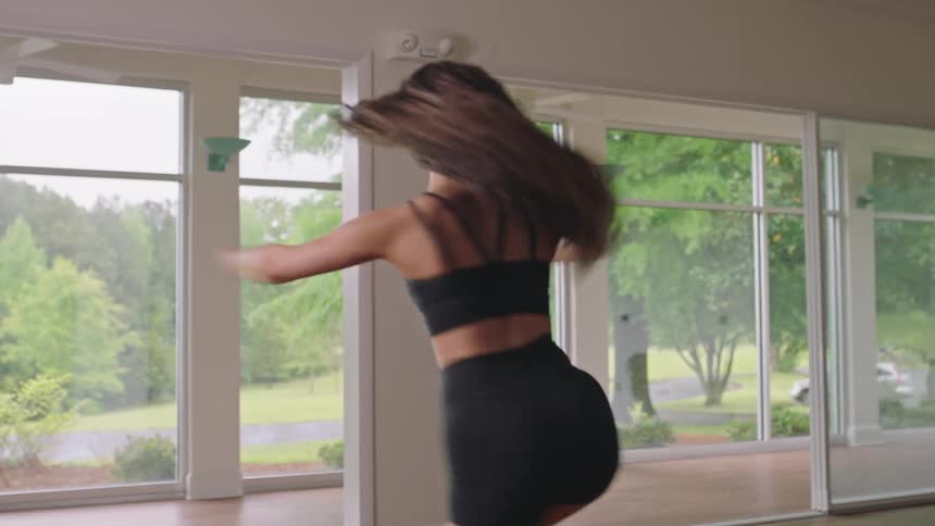 A young performs a dance move in an empty room