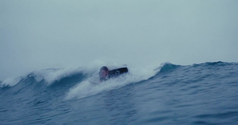A surfer catching then riding a wave