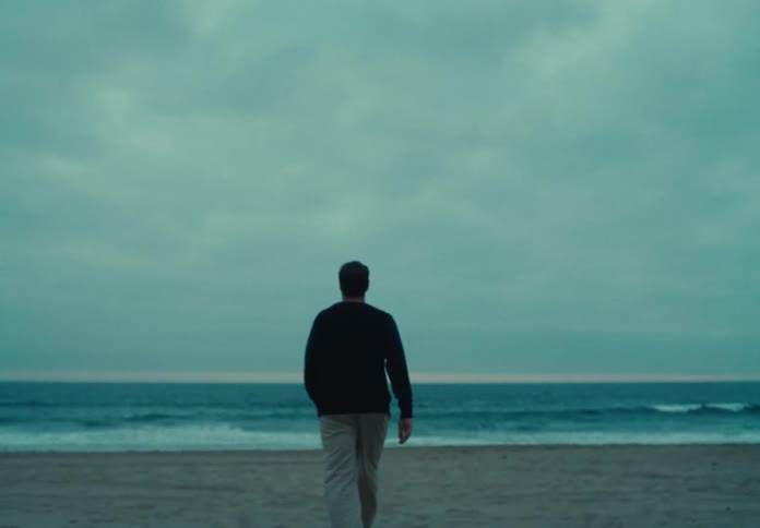A man walks across a beach toward the ocean