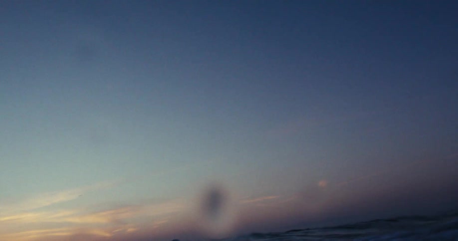 A wave crashing at sunset