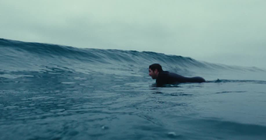 Man diving a wave with his surfboard in the middle of the ocean on a cloudy day