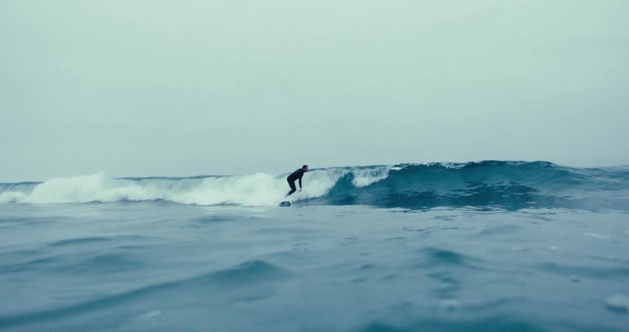 A man is riding a wave on his surfboard