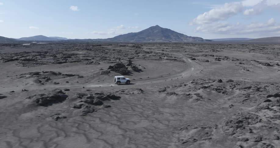 A vehicle navigates a road on a desolate plain