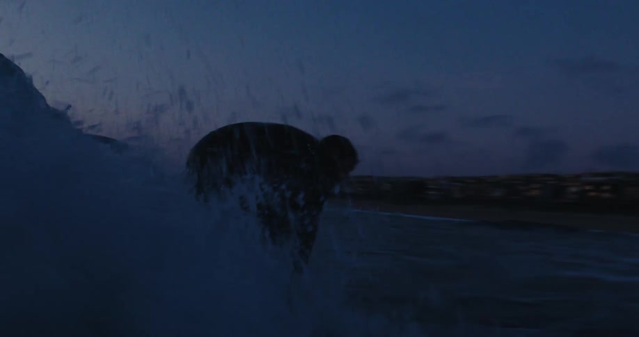 Silhouette of a man preparing to catch a wave with his surfboard one morning on his purple
