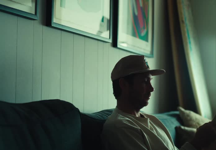 A man sits on a couch leafing through a publication