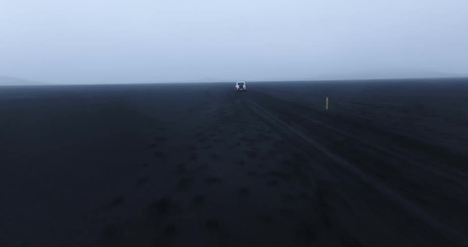 White jeep traveling on black soil and a foggy day