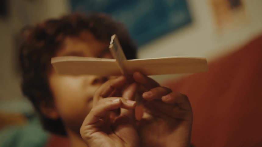 Boy sitting playing with a small paper airplane