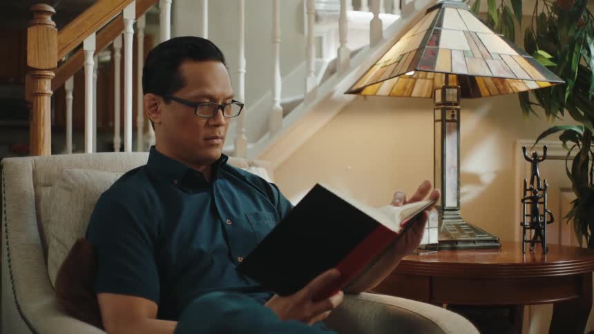 A man sitting on a couch reading a book