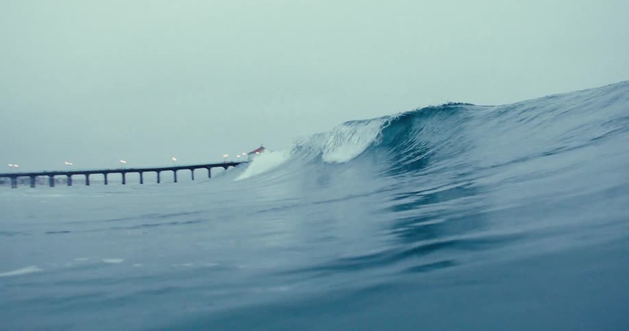 An ocean wave rolling near a wooden pier