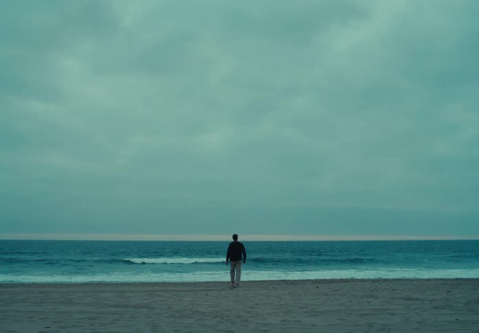 A man on a beach walks to the water