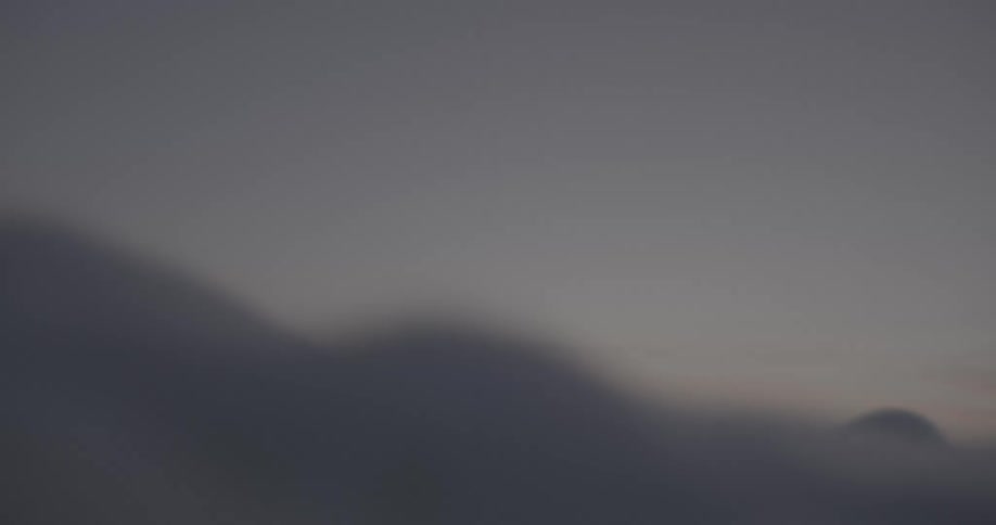 A surfer floating in the ocean at dusk