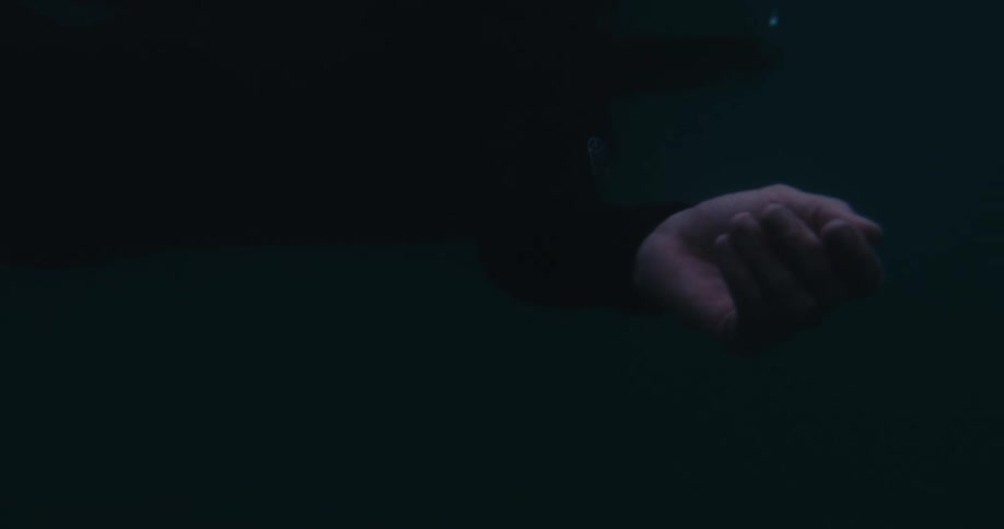 Underwater footage of a hand moving in dark waters