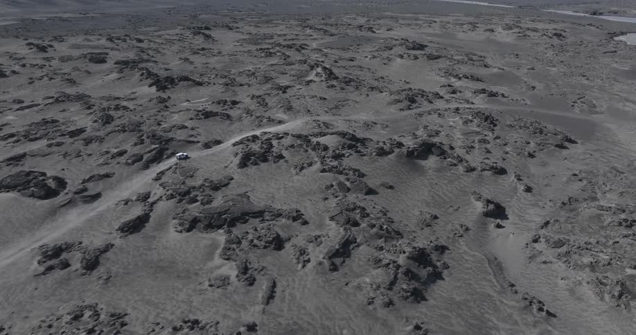 A vehicle drives across a vast lava field