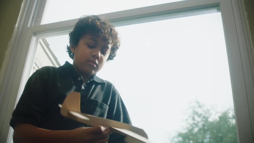 Little boy playing with a plane made of cardboard