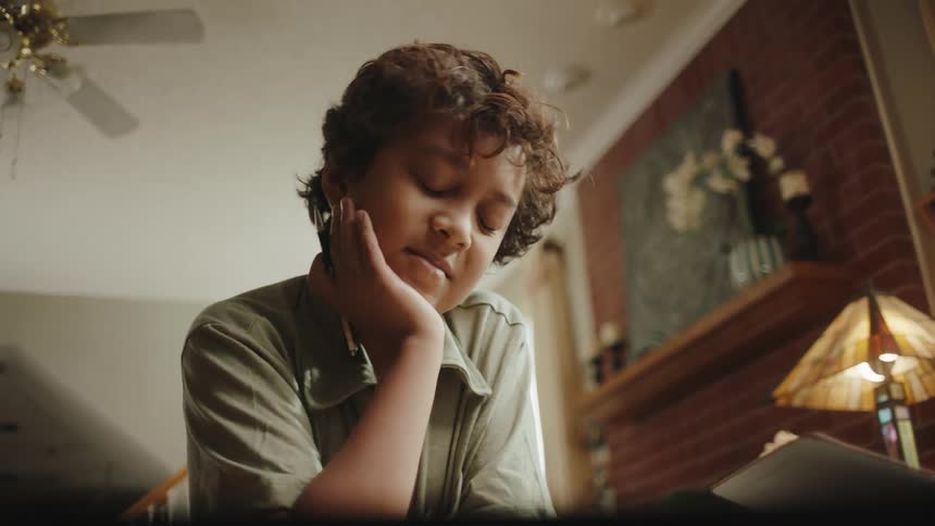 Boy sitting holding a pen and reading