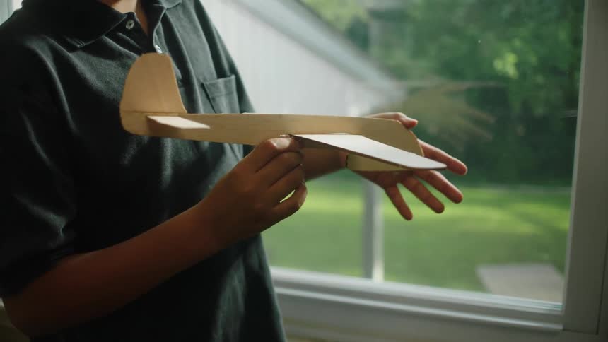 A boy holding a wooden toy airplane