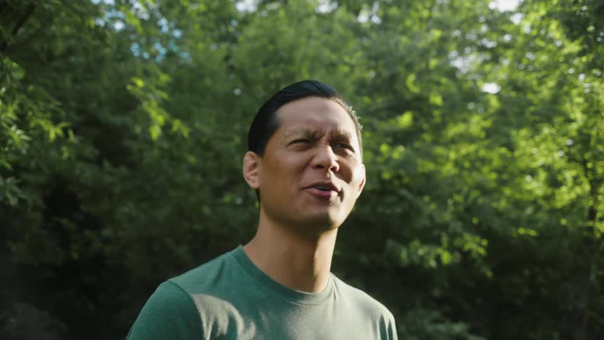 A man wearing a green shirt talking in the backyard at morning