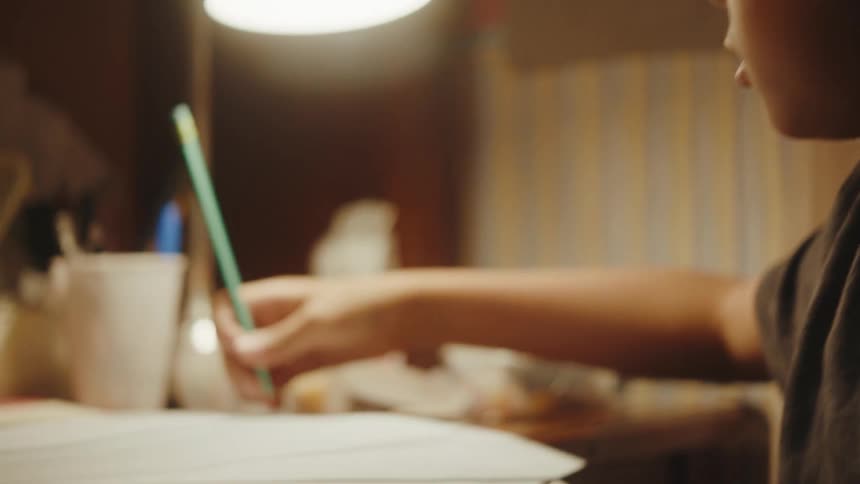Boy sitting at a table drawing with a pencil