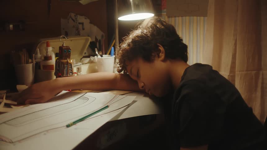 A young boy asleep at a desk