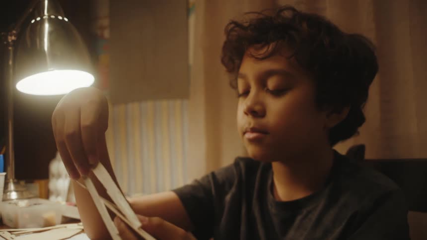 A boy holding pieces of a wooden toy model trying to see how they fit together