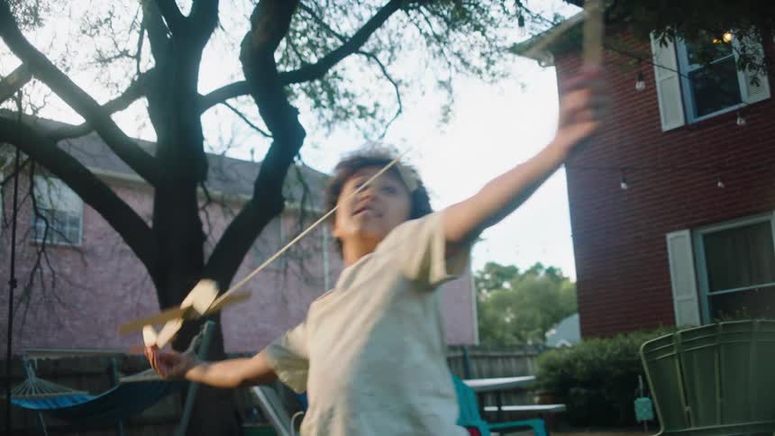 Little boy in the backyard playing with the cardboard airplane