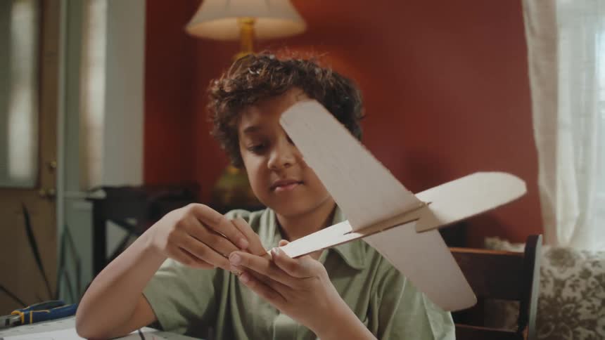 A boy making toy paper planes in the living room