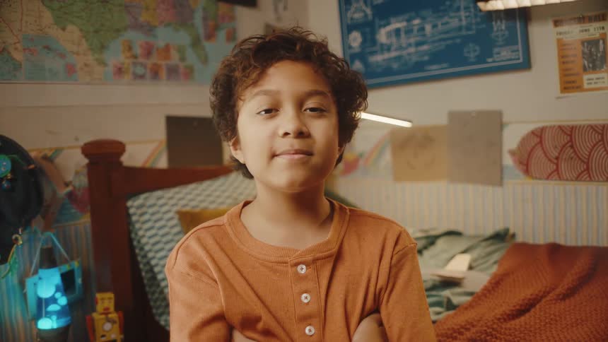 A child standing in his room looking at the camera