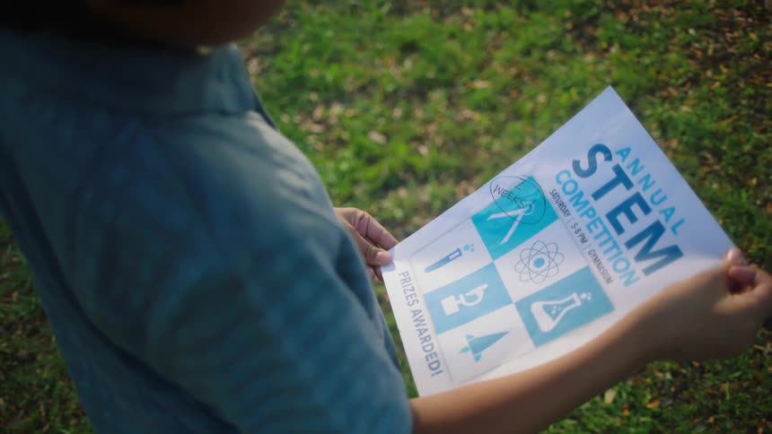 Young boy holding a flyer about an annual stem competition
