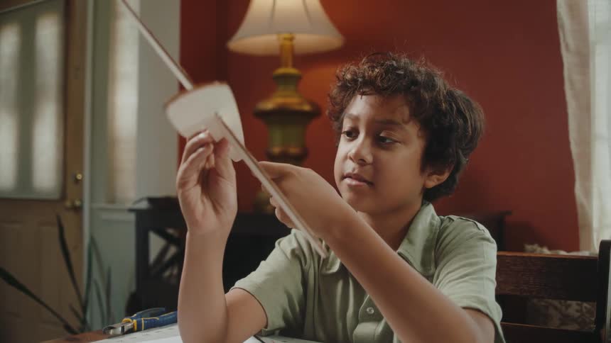 A young boy figures out how to build a cardboard airplane