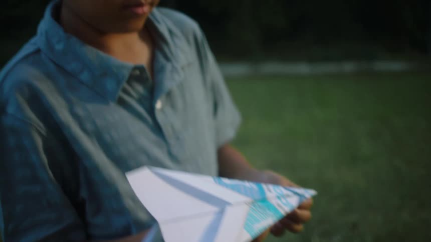 A boy making and throwing a paper airplane