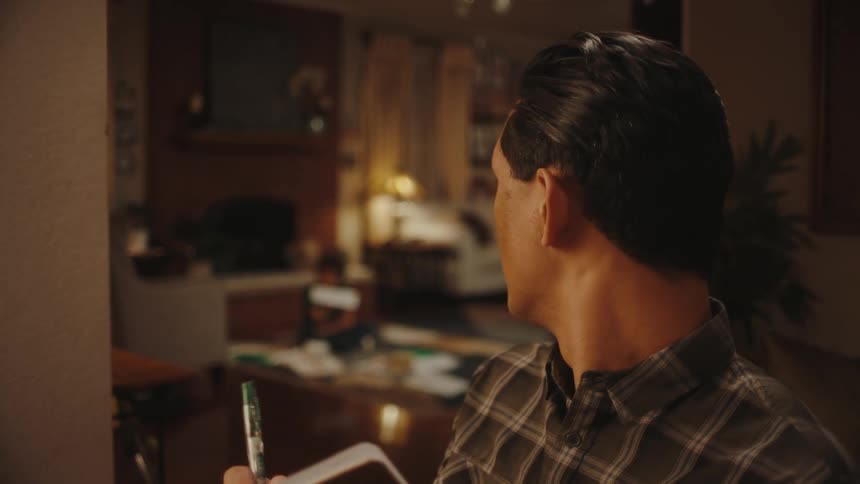 Portrait of the father writing in a book and in the background his son playing in the living room