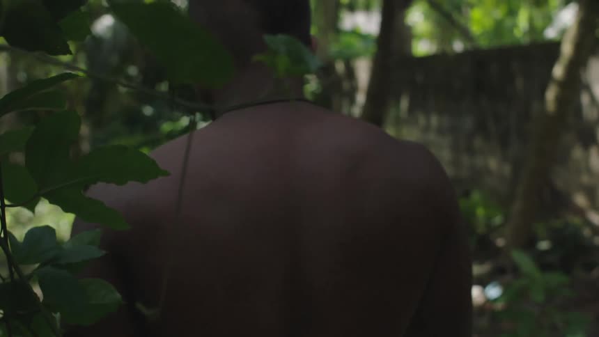 A black man walks through a forest