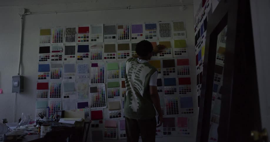Man standing in office considers fabric samples hanging on wall