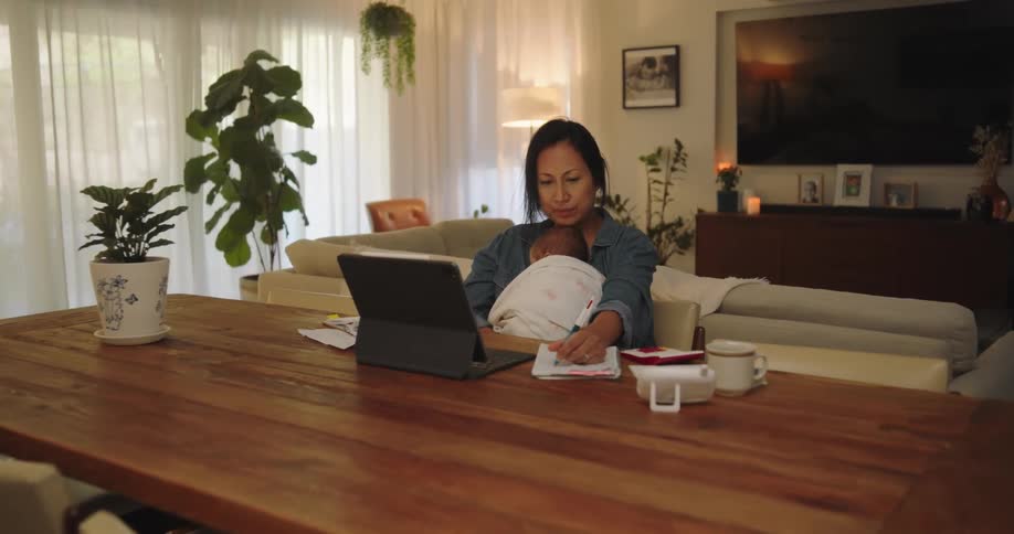 Mother holds infant while working from home